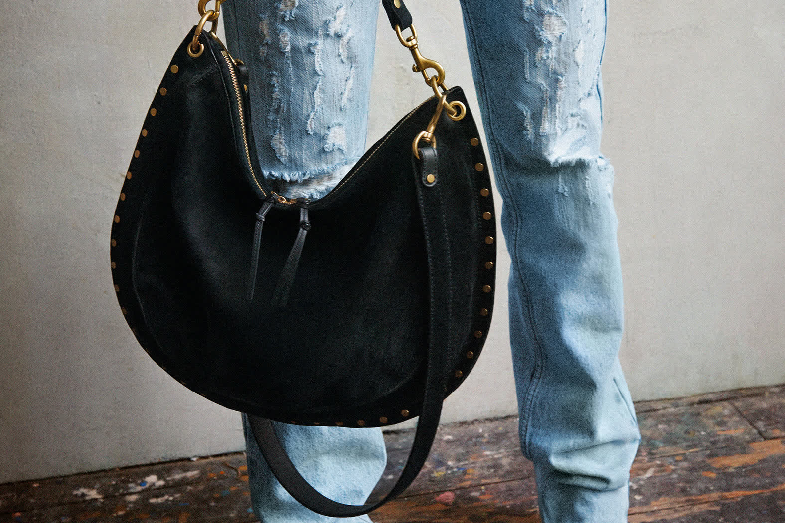 Black suede bag beside torn denim